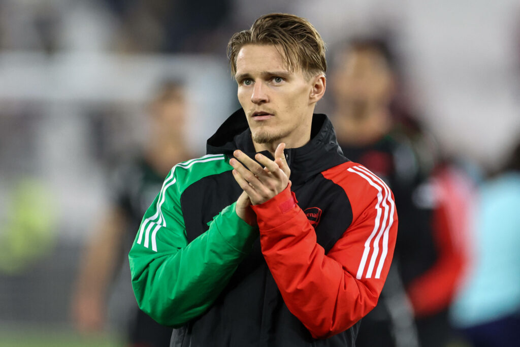 Martin Odegaard clapping while wearing an Arsenal coat